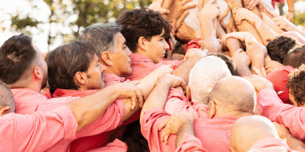 Participants in a traditional Catalan human tower, or “castell,” stand shoulder to shoulder in red shirts, locking arms to support climbers above. This centuries-old practice, recognised by UNESCO as Intangible Cultural Heritage, symbolises strength, trust, and collective identity in Catalan culture.
