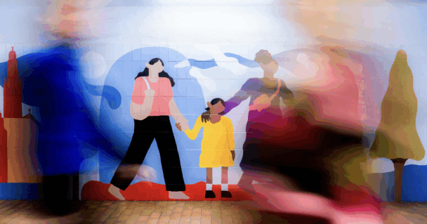 A mural of a family holding hands on the wall of a tunnel, as blurred people walk by.