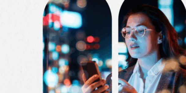 Gemini said An image of a person with glasses and dark hair looking at a smartphone screen, which illuminates their face with a cool blue light. They are positioned behind a series of arched window frames that look out onto a vibrant, blurred cityscape at night filled with colorful bokeh lights. The scene suggests a modern, urban atmosphere focused on technology and connectivity.