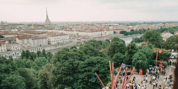 A picture of the city of Torino from high up. A forest can be seen, as well as outside works of art and the city centre in a picturesque scene.